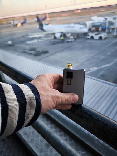 In the picture, a patient holds a vaporizer in their hand, while an airplane and the airport are visible in the background. (Subtitled by AI)