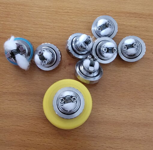 Az asztalon többféle fém és mƱanyag alkatrész låtható, melyeken fehér vatta van tekerve. (Feliratozva AI-val)