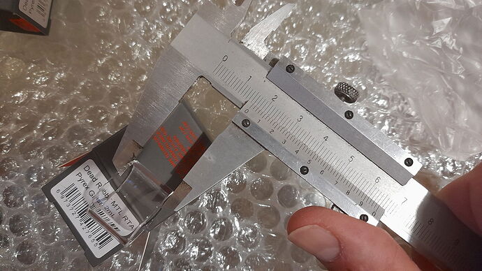 Egy kéz műszeres tolómérővel egy kis, címkével ellátott üvegprizma átlóját méri. (Feliratozva AI-val)