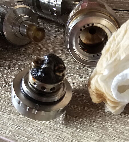 Az image egy részletes közeli kép egy elektronikus cigaretta atomizátoráról, amelyen látható egy elhasználódott és korommal borított fűtőszál. (Feliratozva AI-val)