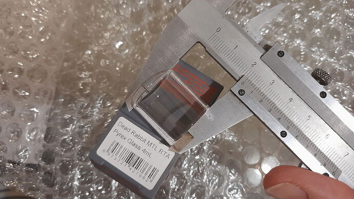 Az képen egy digitális tolómérő látható, amint egy kis üvegcserélő tartozék méretét méri egy doboz mellett. (Feliratozva AI-val)