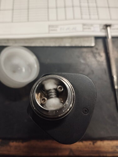 The image shows a close-up of an electric cigarette (vape) tank, displaying a coiled heating wire and cotton wick. (Captioned by AI)