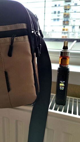 The image shows a bag and an electronic cigarette, the latter standing on a radiator. (Subtitled by AI)