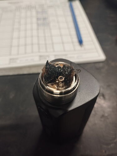 An image depicts an electronic smoking device (vape) with an exposed heating coil and burn marks at the top. (Captioned by AI)