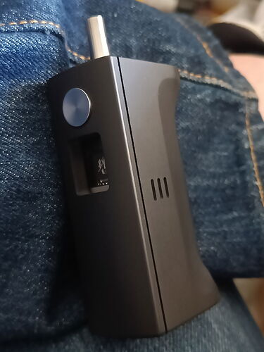 Un vaporisateur ou une cigarette électronique noire tenue à la main au repos sur un jean. (Légendé par IA)