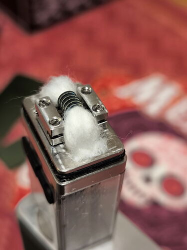 A képen egy vape eszköz látható, amelynek felső részén vattával töltött kohászati tekercs található. (Feliratozva AI-val)