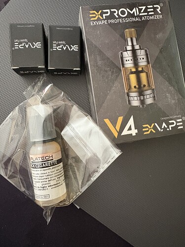 In the picture are two boxes of EVOKE, an EXPROMIZER V4 EXVAPE PROFESSIONAL ATOMIZER, as well as a bottle of vape e-liquid are visible. (Captioned by AI)