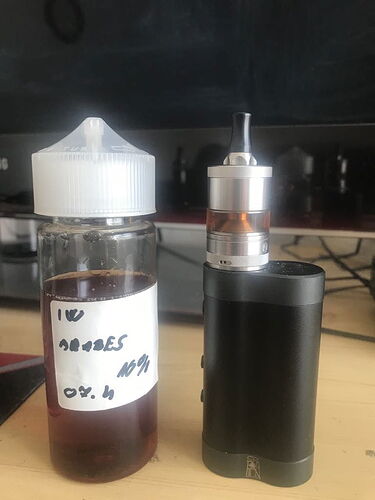 A bottle of e-liquid and a black electronic cigarette mod are visible on the table. (Labeled by AI)