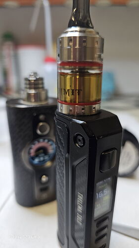 L'image montre un appareil de vape noir avec un liquide jaunâtre dans son réservoir. (Légendé par l'IA)