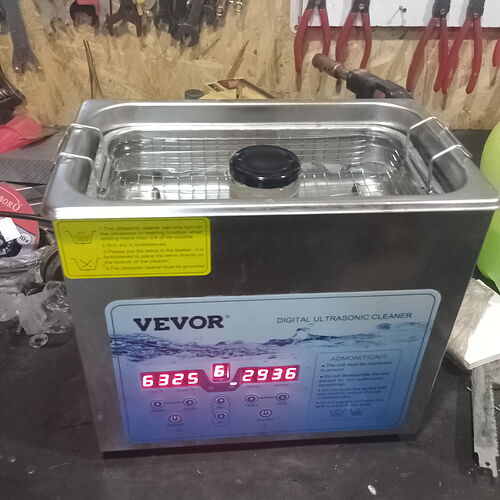 Un nettoyeur à ultrasons numérique Vevor sur un établi, avec des outils en arrière-plan. (Légendé par IA)