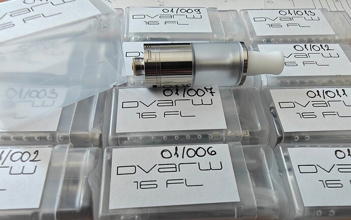 Az képen több, Dvarw 16 FL feliratú műanyag tokban tárolt e-cigaretta tartályok láthatók, melyek közül az egyik ki van csomagolva. (Feliratozva AI-val)