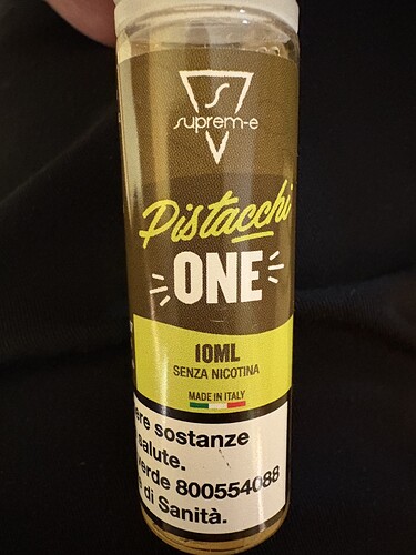 Ez a kép egy 10 ml-es, Pistacchio ízesítésű, nikotinmentes e-liquid üvegét ábrázolja, amely Olaszországban készült. (Feliratozva AI-val)