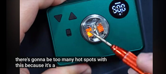 A green electronic device is shown, with someone fine-tuning a coil containing resistance wires using a red screwdriver, while the display shows a number. (Captioned by AI)