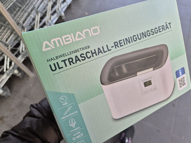 L'image montre la boîte d'un appareil de nettoyage à ultrasons de marque Ambiano, fonctionnant à demi-onde. (Légendé par IA)