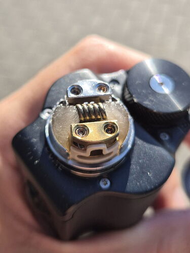 Close-up of a hand holding an e-cigarette with a heating coil and holder. (AI-generated caption)