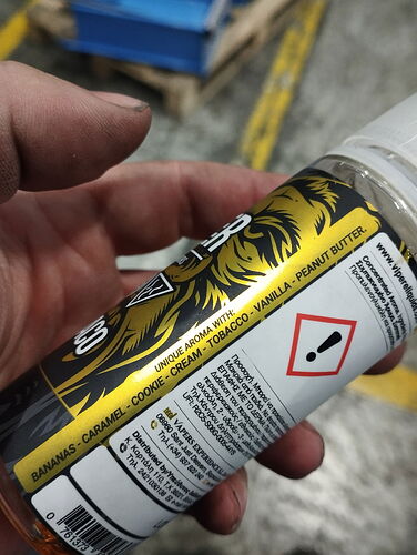 L'image montre une bouteille de liquide aromatisé avec la mention BANANAS - CARAMEL - COOKIE - CREAM - TOBACCO - VANILLA - PEANUT BUTTER, ainsi qu'un avertissement sur les précautions. (Légendé par IA)