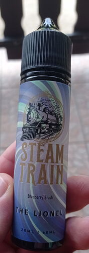 Une bouteille d'e-liquide saveur myrtille (Blueberry Slush) intitulée « Steam Train » est visible sur l'image, représentant une locomotive à vapeur. Le nom du produit est « The Lionel ». (Légendé par IA)