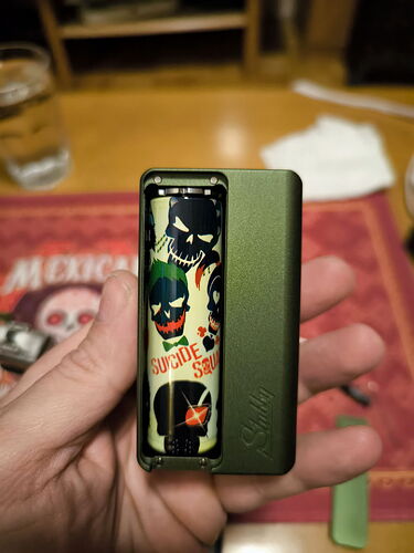 A green, labeled electronic cigarette is shown in the image with its case open, displaying various dark characters. (Autogenerated by AI)