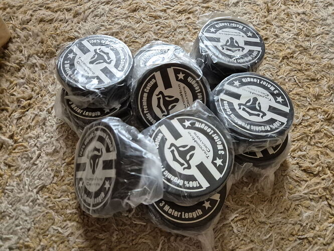 Sur l'image, plusieurs paquets d'autocollants ronds avec des logos noir et blanc sont visibles sur un tapis. (Légendé par l'IA)