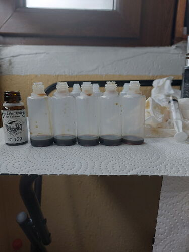 Az képen néhány üres fehér üveg látható, amelyek alján sötét folyadék található, mellettük egy sötétebb üveg és néhány papírtörlő. (Feliratozva AI-val)