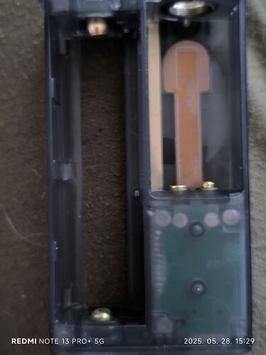 In the picture, the internal circuitry of an open remote control and the empty battery compartment are visible. (Labeled by AI)