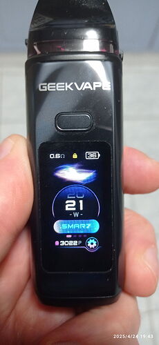 L'écran d'un appareil de cigarette électronique GEEKVAPE tenu dans une main, affichant divers réglages et données. (Légendé par IA)