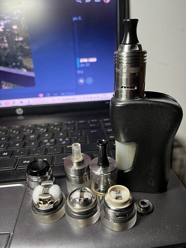 Un vaporisateur noir et plusieurs pièces d'atomiseur différentes sont disposés sur le clavier d'un ordinateur portable. (Légendé par IA)