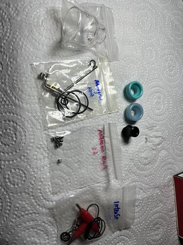 L'image montre diverses pièces emballées, y compris des écouteurs, des vis et d'autres petits objets. (Légende par IA)