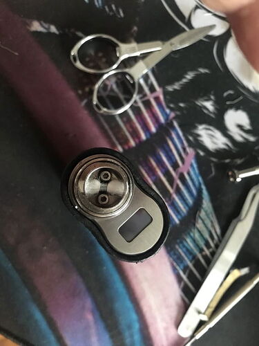 Une cigarette électronique, des ciseaux et une pince visibles sur une table. (Description IA)