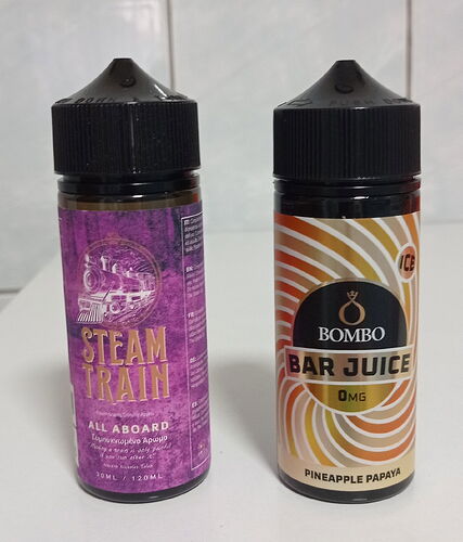 Két, 120 ml-es aromás e-folyadék palack áll egymás mellett, az egyik STEAM TRAIN, a másik BOMBO BAR JUICE márkájú. (Feliratozva AI-val)