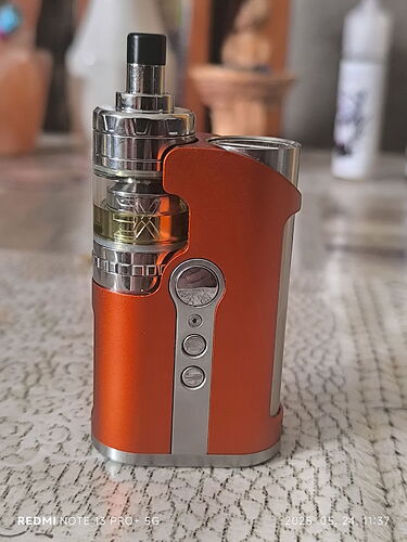 Sur l'image, une cigarette électronique (vape) de couleur orange et argentée est visible sur une table. (Légendé par IA)