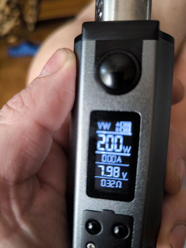A hand holding an electronic vaporizer, with various mode settings and values displayed on its screen. (Subtitled by AI)
