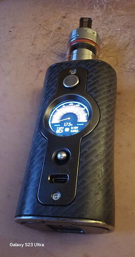 Az képen egy digitális kijelzővel ellátott, szénszálas mintázatú elektromos cigaretta (vape) látható. (Feliratozva AI-val)