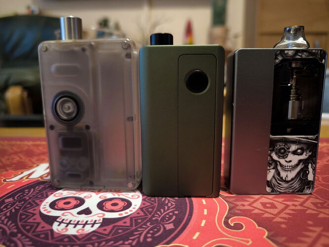 Three different vape devices are shown standing next to each other on a colorful, skull-patterned background. (Autogenerated by AI)