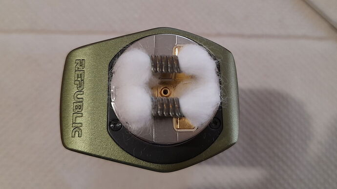 The image shows a close-up of a REPUBLIC brand electronic cigarette coil and cotton build. (Subtitled by AI)