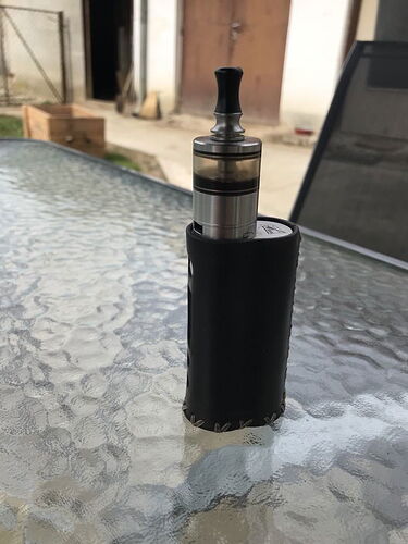 Az asztalon egy fekete bőrtokkal borított e-cigaretta áll egy üveglapon. (Feliratozva AI-val)