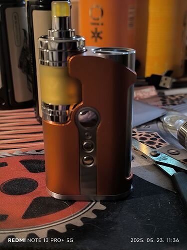 L'image montre un appareil de cigarette électronique (vape) de couleur marron sur une table avec divers éléments d'arrière-plan. (Légendé par IA)