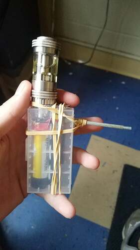 Sur la photo, un appareil tenu à la main, maintenu par des tiges et des cordes élastiques, intégré dans une boîte en plastique transparent avec un réservoir métallique est visible. (Légendé par IA)