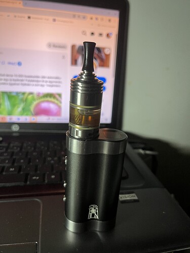 An e-cigarette stands on a laptop keyboard, with a website visible on its screen. (Subtitled by AI)