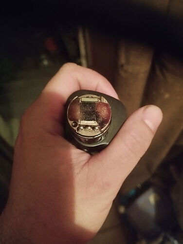 A hand holding the bottom of a black e-cigarette (vape) in a close-up photo. (Labeled by AI)