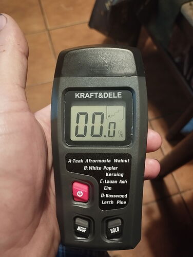 Un appareil de mesure d'humidité numérique KRAFT&DELE tenu dans la main est visible, montrant une valeur d'humidité de 0,0 %. (Sous-titré par IA)