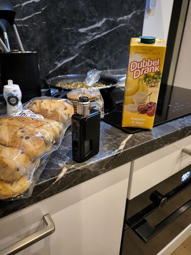 La photo montre un comptoir de cuisine avec des pâtisseries, une boîte de boisson et une cigarette électronique. (Légendé par IA)