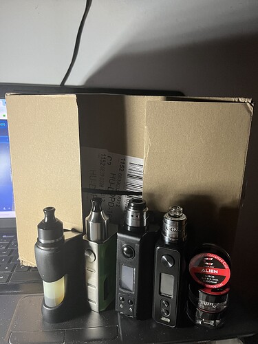 More vaporizers and coils are visible in the picture in front of a cardboard box and a laptop. (Subtitled with AI)