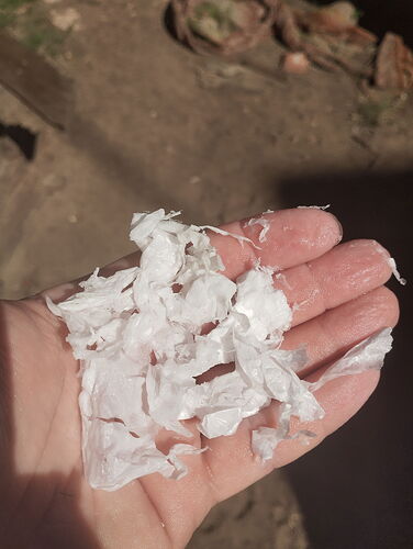 Egy kéz gyűrött, fehér anyagdarabkákat tart a tenyerében. (Feliratozva AI-val)