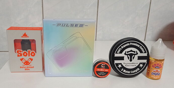 Az asztalon különböző vape tartozékok és egy e-liquid üveg helyezkedik el. (Feliratozva AI-val)