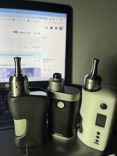 The image shows three electric cigarettes (vapes) of different designs in front of a laptop. (Labeled by AI)