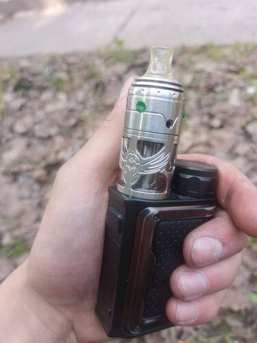 A hand holds a metal vape device with a black body and a silver tank. (AI-generated caption)