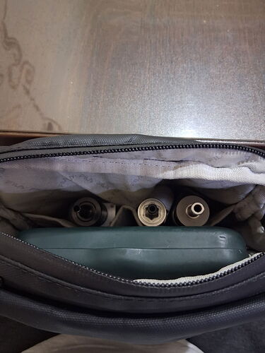 L'intérieur d'un sac est visible sur la photo, avec divers fils et un appareil verdâtre. (Légendé par IA)