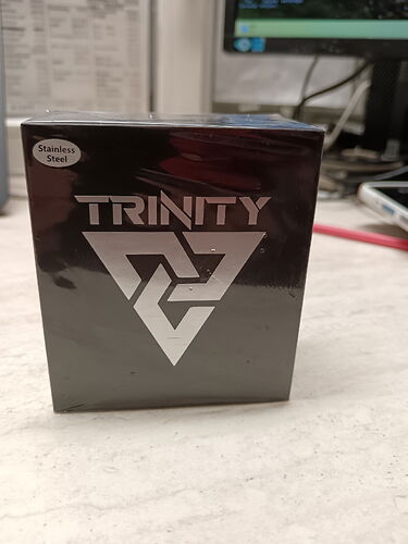 Une boîte noire est visible sur l'image, avec l'inscription "TRINITY" et un logo triangulaire. (Légendé par IA)