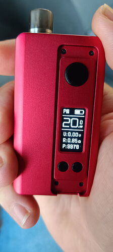 Egy kézben tartott piros elektronikus eszköz látható, amelynek kijelzőjén a '20.0' érték, akkumulátorjelző és egyéb információk jelennek meg. (Feliratozva AI-val)